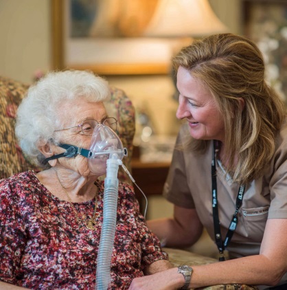 Caregiver supporting an elderly woman receiving oxygen therapy at home through home health care Bedford Indiana.