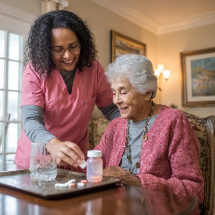 Caregiver assisting elderly woman with medication routine at home in Greenfield, IN.