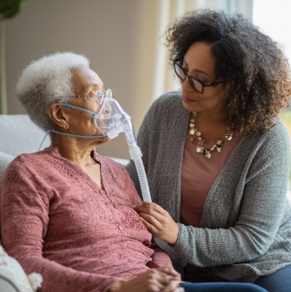 Caregiver assisting elderly woman with oxygen therapy at home in Kokomo, IN.