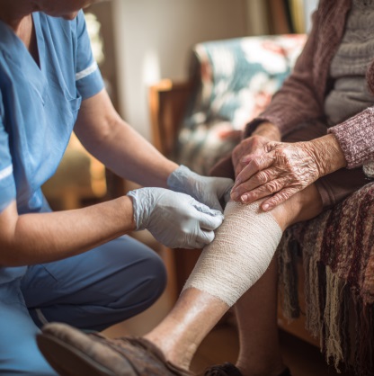 Nurse providing wound care to elderly patient at home in Bedford, Indiana.