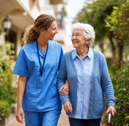 Caregiver walking beside smiling senior woman during home health support in Kokomo, IN.
